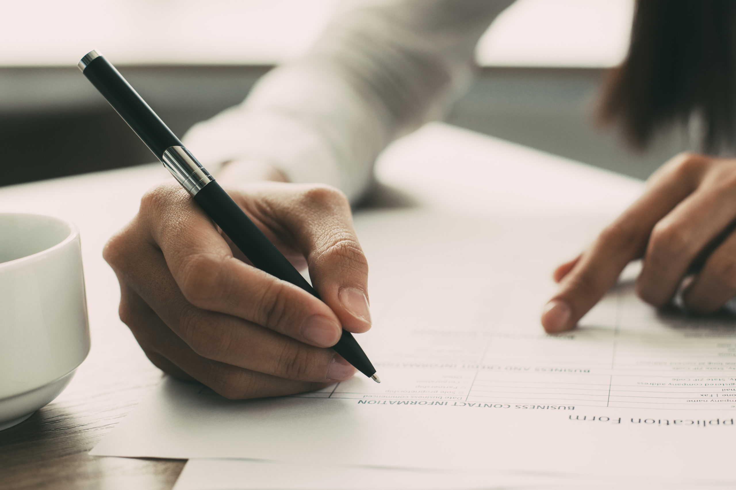 close-up of woman holding a pen and filling out an application form