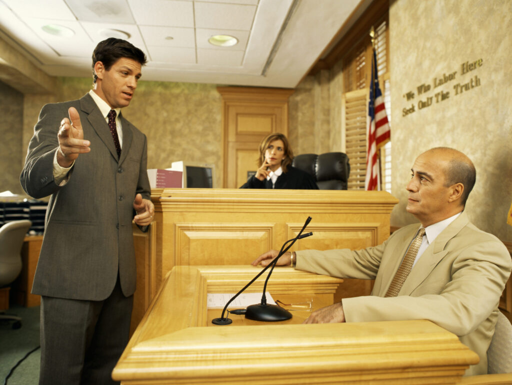 Side profile of a lawyer and a witness on the stand with judge in background