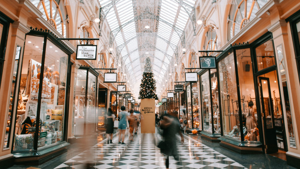 Holiday shopping consumers explore the storefronts of a mall.