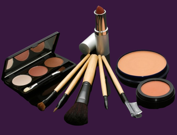 lipstick, eyeshadow, blush, and makeup brushes with a purple background