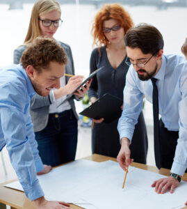 engineers discussing a blueprint around a desk